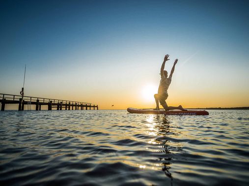 Mann macht Yoga auf dem Wasser auf einem SUP-Board 