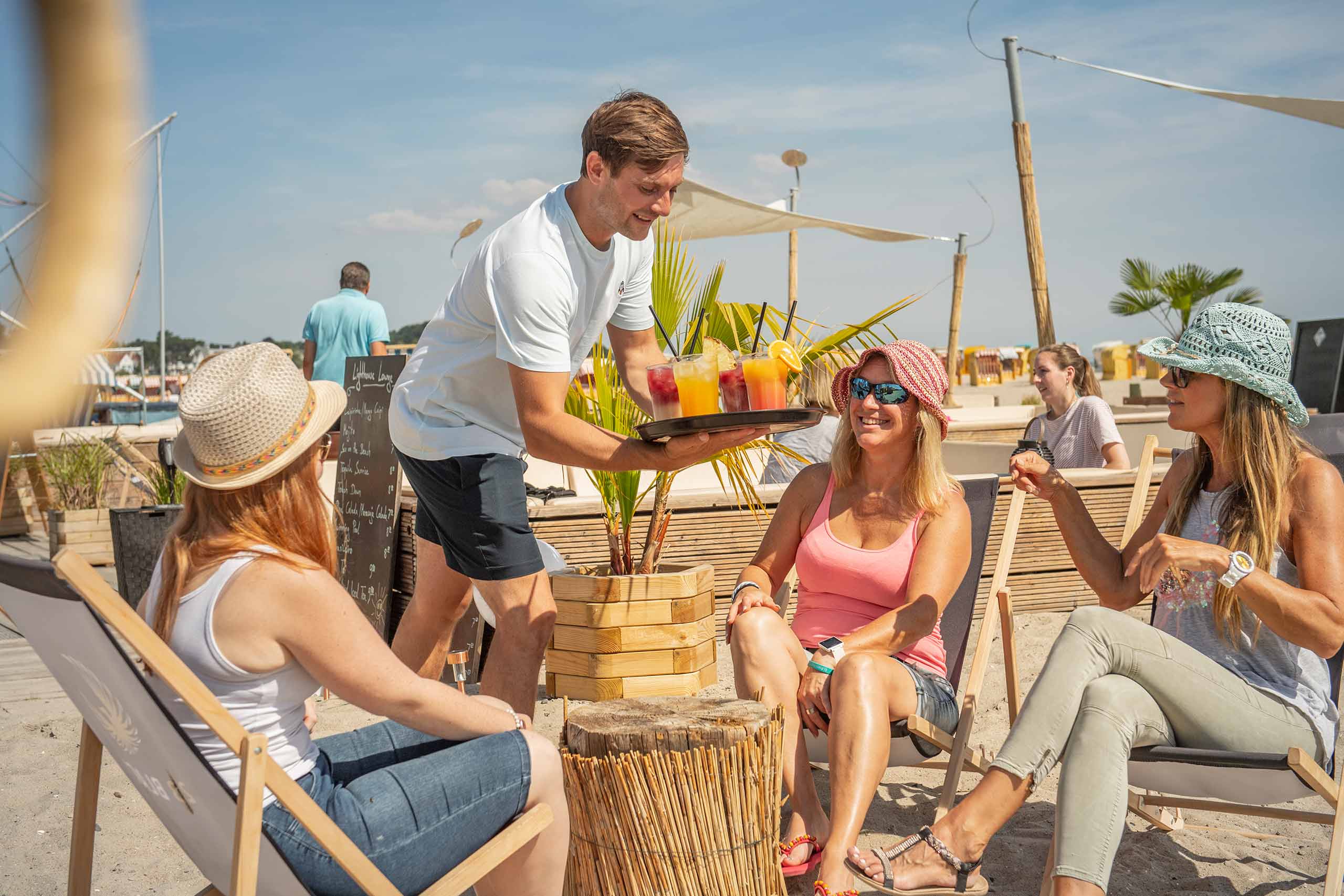 Bedienung serviert Cocktails an eine Gruppe in der Beachlounge