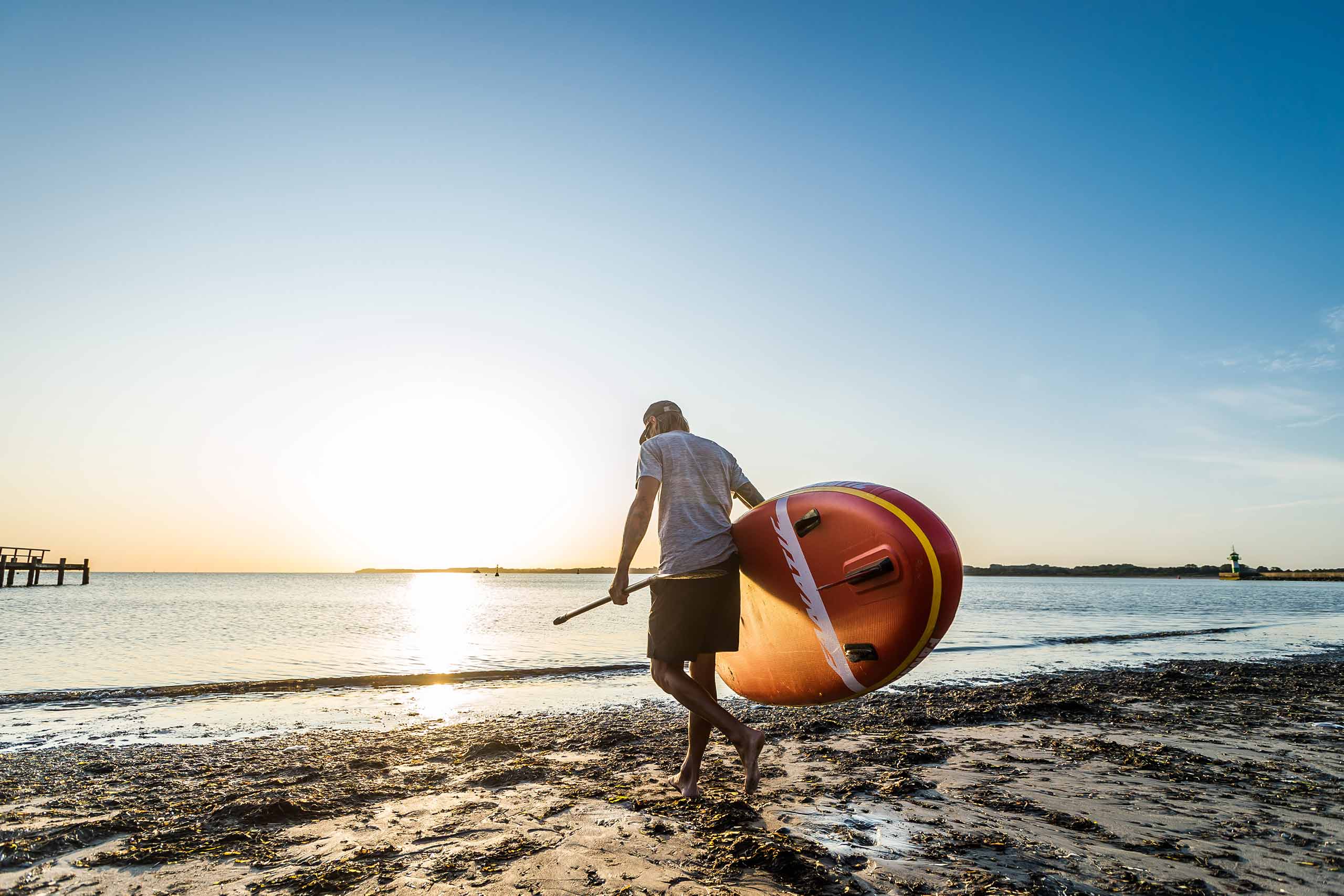 Mann mit SUP Board am Strand