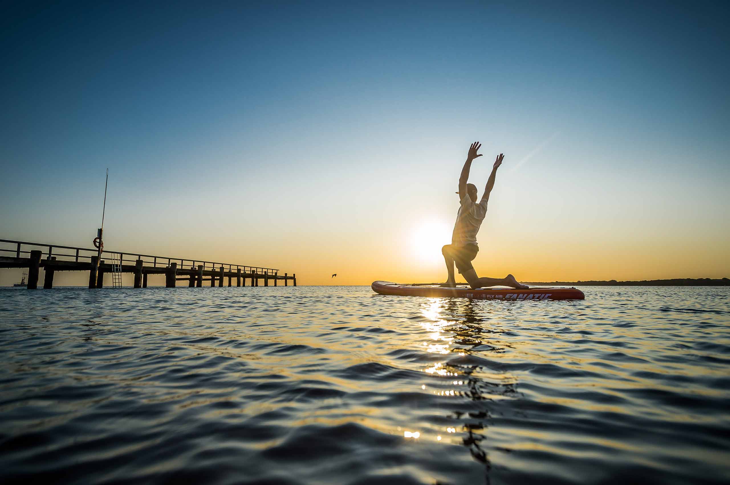 Mann macht Yoga auf dem Wasser auf einem SUP-Board