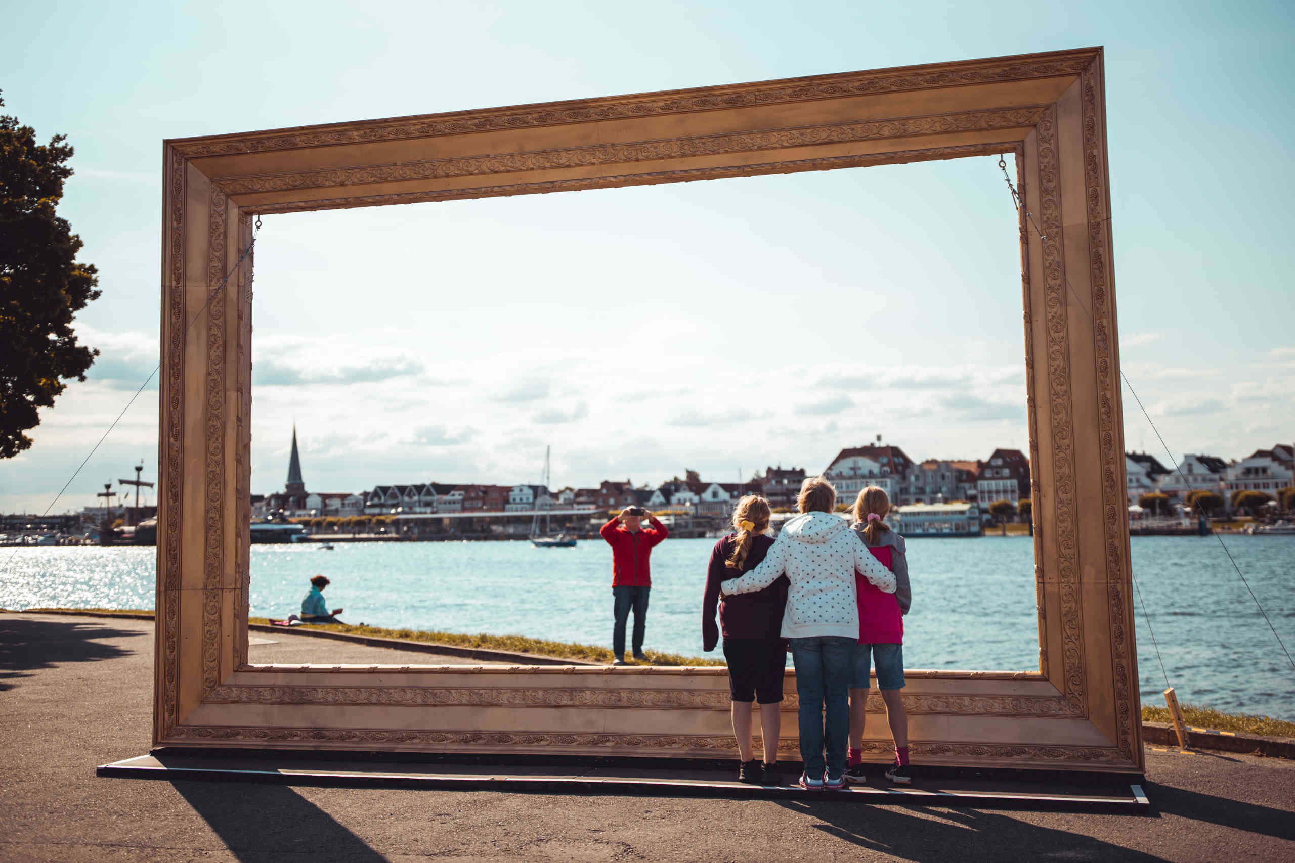 Familie macht ein Foto bei einem großen goldenen Bilderrahmen am Priwall