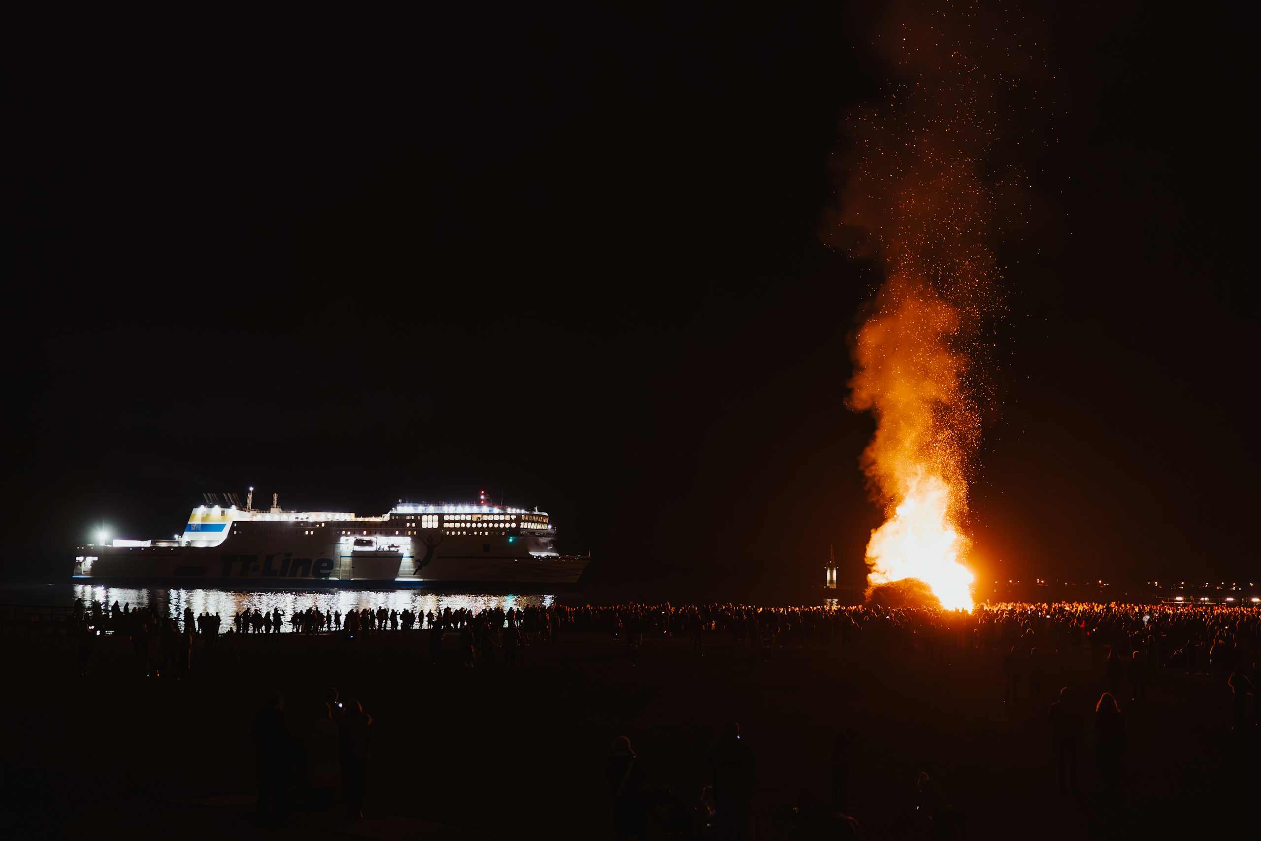  Das Osterfeuer am Strand von Travemünde. Im Hintergrund fährt ein Schiff der TT-Line in den Hafen ein.